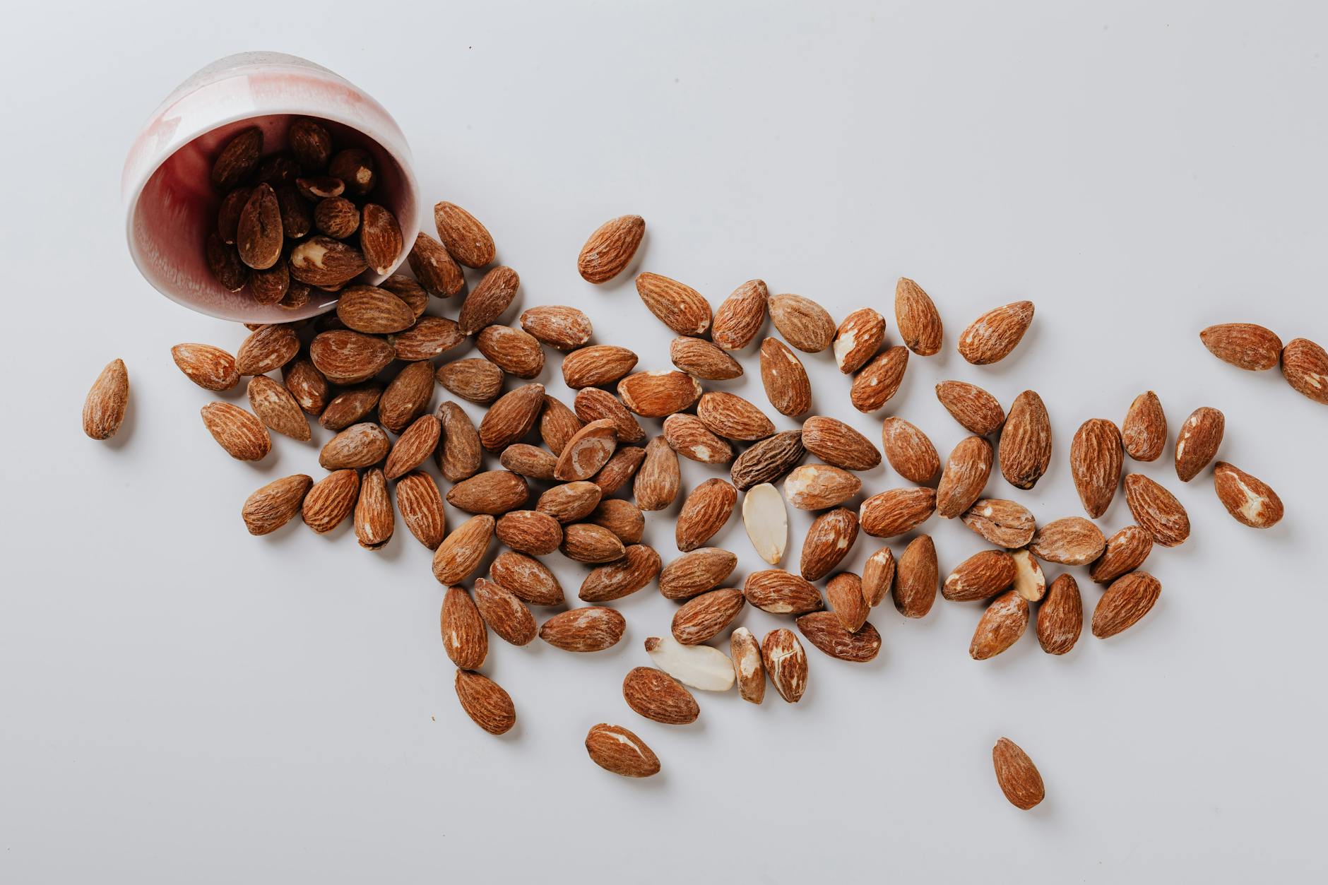 raw almonds spilled out of small ceramic bowl