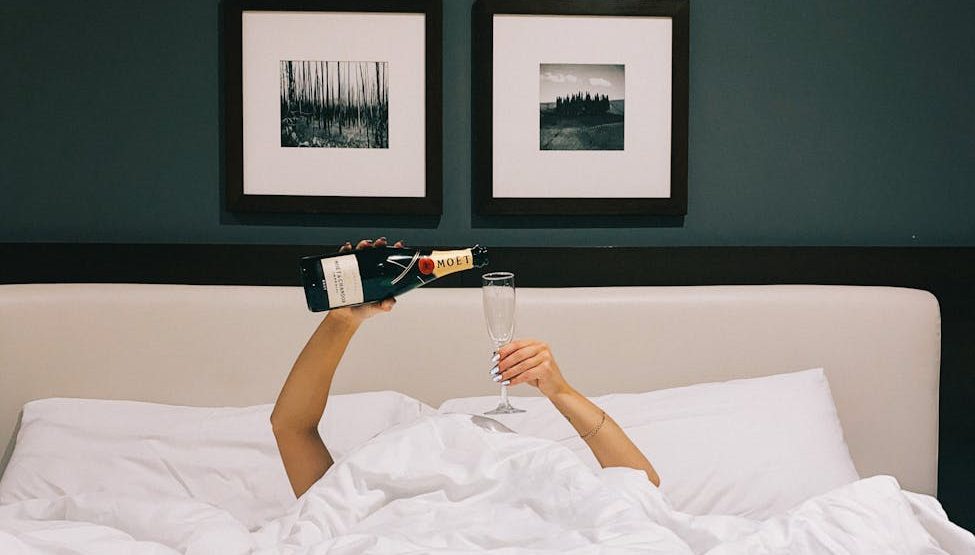 woman pouring champagne in a bed