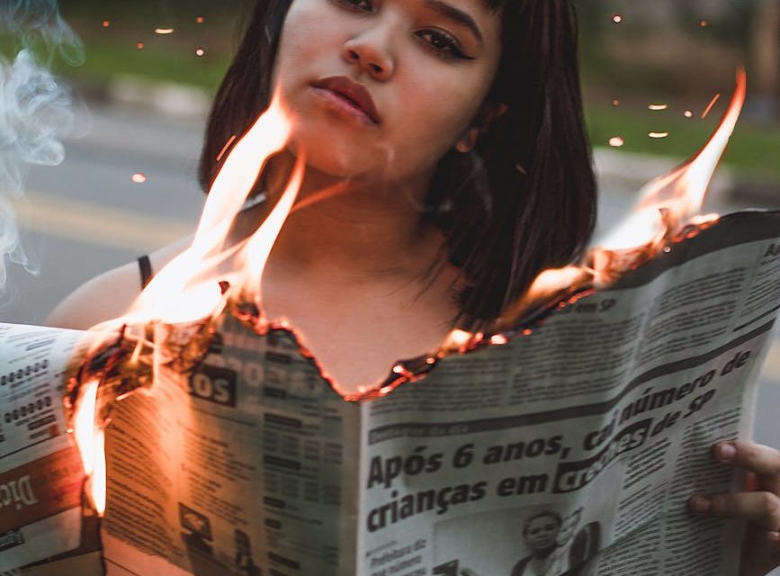 woman holding burning newspaper