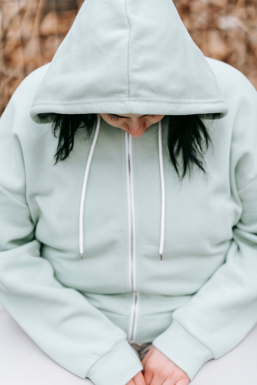 sad woman in a hoodie sitting in a park bench