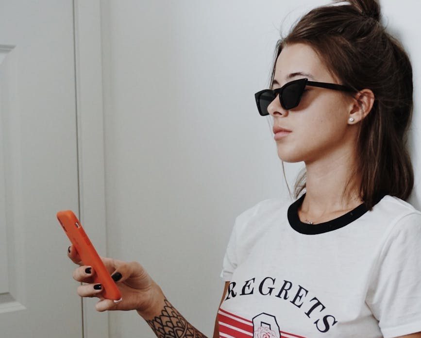 woman wearing black sunglasses holding android smartphone
