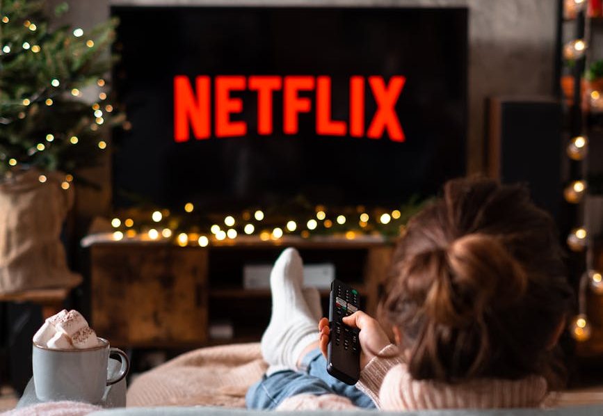 back view of a woman sitting on a sofa and watching television